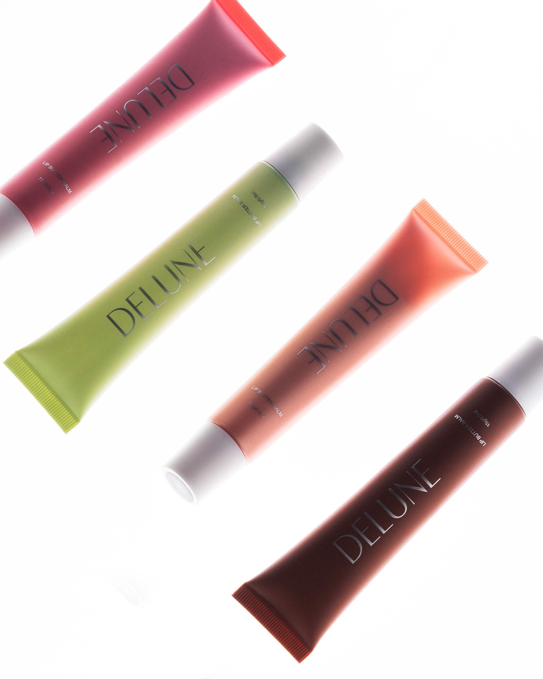 Four Delune Lip Butter Balm shades with glossy swatches